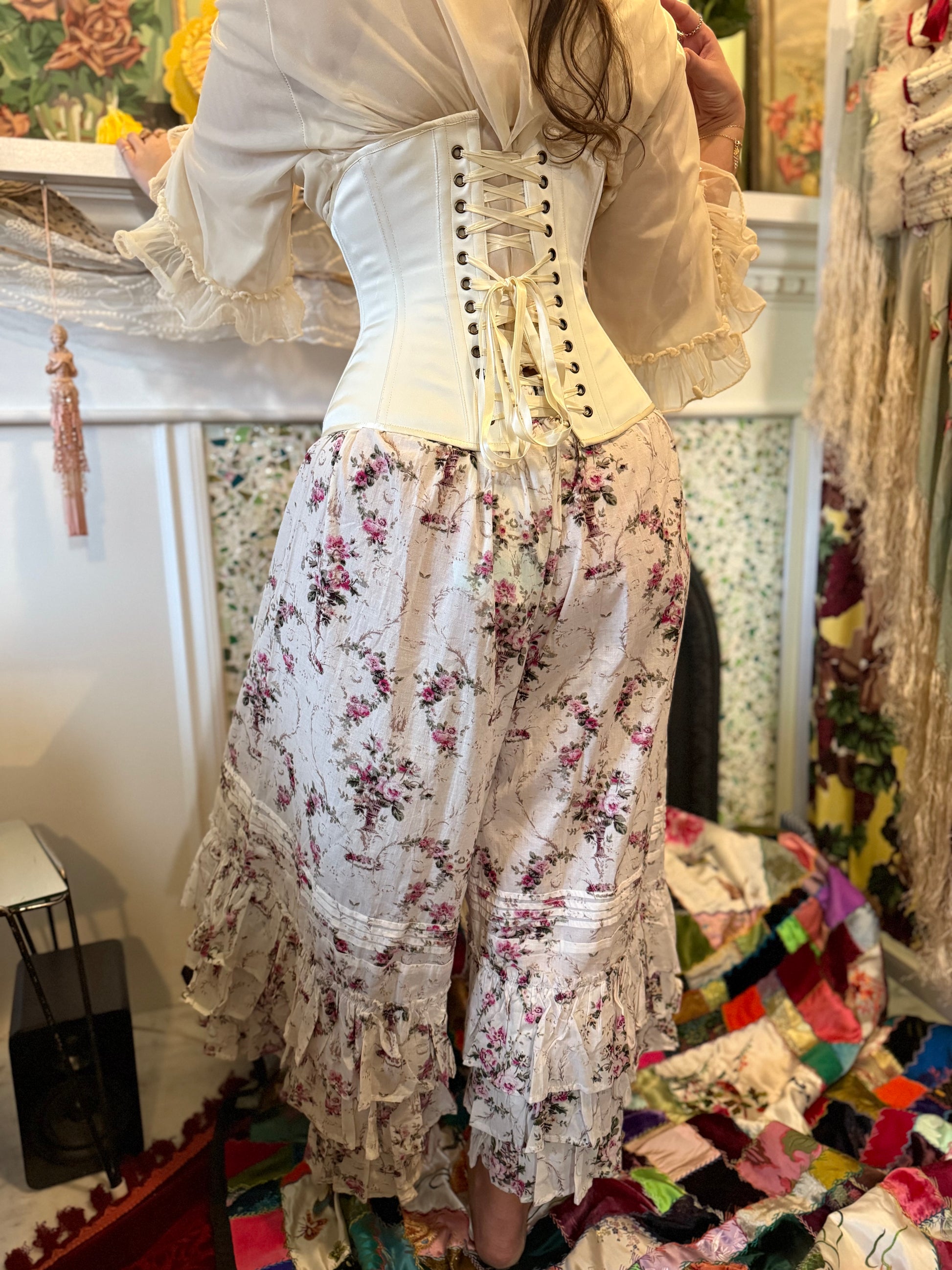 Person wearing a floral outfit with the ivory satin  cincher corset in a decorative room.