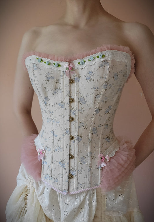 pale blue rose cotton corset with pink tulle hip ruffles, trimmed with blue ribbon roses and dotted bows